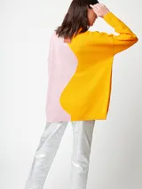 Cárdigan de punto fino bicolor, con un lado amarillo y otro rosado. Tiene bolsillos delanteros y cierre con botones de madera.