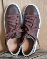 Zapatillas plateadas de cuero con cordones grises y suela blanca.