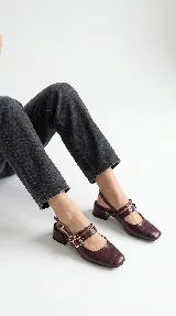 Zapato de tacón bajo destalonado de cuero bordó con textura croco, punta cuadrada, doble tira en el empeine con hebillas metálicas doradas y taco bloque.