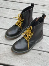 Bota corta de cuero color chocolate, con cordones amarillos y cierre lateral.