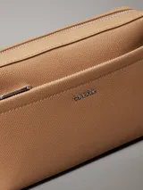 Bandolera Calvin Klein color tostado, con correa ancha de tela con logo de la marca y correa fina de cuero sintético.