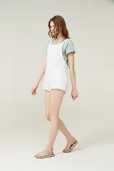 Mono corto color amarillo pastel, con breteles finos que se atan en los hombros, escote recto y dos bolsillos delanteros.