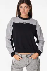 Buzo de cuello redondo con diseño de bloques de color en gris y negro, mangas largas y detalle bordado en el pecho.