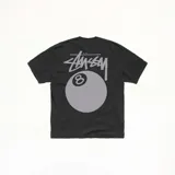 Camiseta de algodón color negro, con corte oversize y cuello redondo acanalado. Presenta un estampado gráfico en la espalda con el logo de la marca Stussy y una bola de billar número 8.