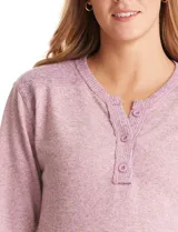 Buzo de tejido fino con escote henley y cierre de botones. Presenta detalles acanalados en hombros, puños y ruedo, con una silueta cómoda y terminación redondeada en la parte inferior.