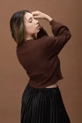 Sweater de punto fino en color marrón, con cuello redondo y mangas largas. Presenta un diseño básico y minimalista con un corte a la cintura.