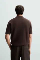 Polo de manga corta, color azul medio, tejido en punto perlado con cuello solapa y cierre frontal de cremallera.