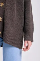 Cardigan de punto en color marrón con escote en V, cierre frontal con botones grandes y mangas largas. Presenta puños y ruedo acanalados.