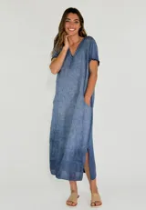 Vestido largo de corte holgado con cuello en V, mangas cortas y bolsillos laterales. Presenta un diseño con efecto desgastado y aberturas laterales en el ruedo.
