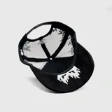 Gorra tipo trucker negra con panel frontal bordado con el logo "LA" en blanco y llamas grises. La visera también presenta bordados de llamas en blanco y gris. La parte trasera es de malla negra y cuenta con cierre ajustable.