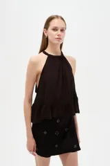 Top blanco de algodón con cuello halter, diseño holgado y detalle de encaje en el borde inferior.