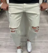Jeans skinny de color beige, con roturas en las rodillas y detalles deshilachados.