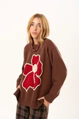 Buzo de punto color chocolate con diseño de flor grande en el frente en tonos rojos y centro texturizado en color crema. Presenta cuello redondo, mangas largas y puños y ruedo acanalados.