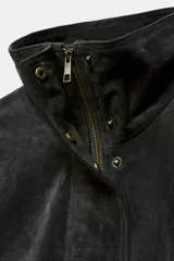 Cazadora de ante con cuello subido, manga larga con puños y bajo elástico. Presenta cierre frontal con cremallera metálica y botones a presión ocultos por solapa, además de bolsillos delanteros.