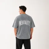 Remera oversize de algodón con efecto stone wash gris, de manga corta y cuello redondo, con estampado en serigrafía en la espalda que dice "Mentality".
