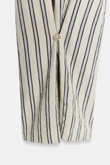 Pantalón de tiro medio con diseño de rayas verticales, confeccionado en mezcla de viscosa. Presenta cintura elástica ajustable con cordones, bolsillos laterales ocultos y pierna recta con bajo ajustable mediante botón.