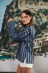 Buzo color beige con rayas horizontales en lurex dorado, cuello con medio cierre, corte oversized y logo tejido en el puño.