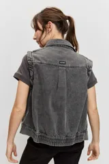 Chaleco de denim color gris deslavado, con cuello camisero, cierre frontal con botones metálicos y costuras decorativas.