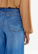 Pantalón de jean azul de corte palazzo con costuras verticales en el frente.