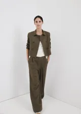 Pantalón de lino verde militar, de diseño recto y tiro alto, con detalle de pinzas y trabillas en la cintura.