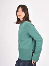 Buzo de tejido de punto color negro, con cuello redondo, mangas largas y puños anchos acanalados. Presenta un diseño con ruedo asimétrico y aberturas laterales.