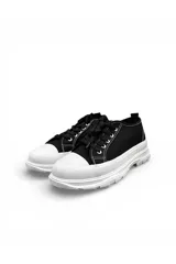 Zapatillas deportivas negras de lona, con suela gruesa tractorada blanca, puntera de goma y cordones al tono.