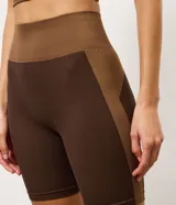 Bermuda deportiva Get Over de microfibra seamless, en color marrón con recortes contrastantes en tono tostado. Presenta cintura alta con pretina ancha cruzada y diseño ajustado.