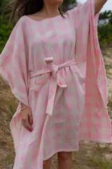 Túnica de corte holgado con estampado a cuadros en tonos rosa y crudo, con cuello redondo y mangas cortas amplias. Incluye cinturón de la misma tela para ajustar a la cintura.