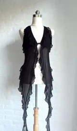 Top halter negro de microtul transparente, con escote en V profundo y bordes con volados o festones. Presenta un cierre frontal central.