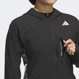 Campera rompevientos Adidas de running, color negro con las clásicas tres tiras blancas en los costados y logo reflectante. Cuenta con cierre frontal, capucha con cordón ajustable, bolsillo en el pecho y diseño entallado con puños con ojal para el pulgar.