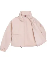 Rompevientos corto Tommy Hilfiger color rosa pálido, con cuello alto, cierre de cremallera, dos bolsillos laterales, detalles distintivos de la marca y logo engomado bordado en la manga.