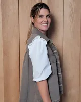 Chaleco de gabardina color tostado, con cuello camisero, cierre frontal con botones metálicos y dos bolsillos frontales con solapa.
