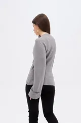 Saco de punto gris con cuello en V, cierre frontal con botones y mangas largas con puños anchos decorados con botones.