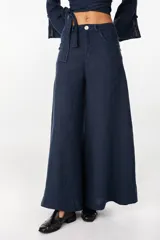 Pantalón de lino verde militar, de tiro alto y corte amplio con botamanga ancha. Cuenta con bolsillos delanteros aplicados y cierre frontal con botón y bragueta.