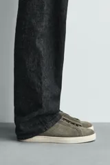 Zapatilla urbana de hombre confeccionada en piel con acabado de serraje, diseño minimalista con cordonera oculta y suela de goma a contraste.