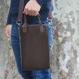 Bolso matero vertical de diseño minimalista, color marrón oscuro, con costuras reforzadas en contraste, doble asa de mano y correa larga ajustable y extraíble.