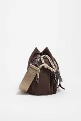Bolso bandolera de nailon marrón de Bimba y Lola, con cierre de cordón ajustable, bolsillo frontal con cremallera y el logotipo de la marca impreso. Cuenta con una correa ajustable ancha de lona beige y detalles de cuerdas decorativas en los laterales.