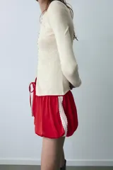 Shorts de tiro medio confeccionados en satén rojo, con diseño tipo globo y cintura elástica ajustable mediante cordones. Presentan detalles de encaje blanco en los laterales.