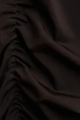 Top de manga larga color marrón oscuro (casi negro), ajustado al cuerpo, con escote redondo y detalle de frunces centrales y laterales que crean un efecto drapeado.