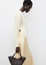 Jersey de punto medio con cuello redondo y manga larga. Presenta un diseño recto con aberturas laterales en el bajo y cierre de lazos en los costados.