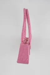 Cartera tipo baguette color negro con textura efecto cocodrilo, diseño alargado, doble asa de mano y cierre superior.
