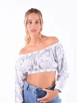 Top corto con hombros descubiertos, mangas largas y estampado floral en tonos celeste y blanco.