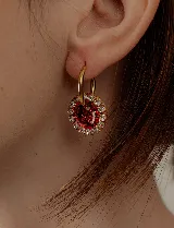 Aros de acero quirúrgico con dije circular de resina rosa y borde de strass dorados.