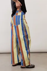 Pantalón de corte ancho y relajado con rayas verticales multicolor en tonos azul, marrón, amarillo, blanco y negro.