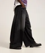 Pantalón de jean color celeste, modelo barrel, de tiro medio con trabillas para cinto, cierre frontal con botón y cremallera, bolsillos, recortes laterales y pinzas en las rodillas.