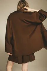 Trench color marrón confeccionado en mezcla de lyocell y lino. Cuello solapa y manga larga. Bolsillos con solapa en delantero. Cierre frontal con botones a presión.