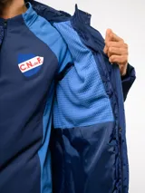 Parka larga acolchada color azul marino con capucha, cierre frontal con botones a presión y bolsillos laterales. Presenta el logo de Umbro y el escudo del Club Nacional de Football bordados en el pecho.