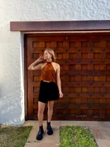 Top halter confeccionado en cuero color camel, con diseño sin mangas, espalda descubierta y ajuste mediante tiras.