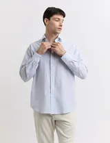 Camisa de vestir a rayas verticales celestes y blancas, de corte clásico y manga larga.