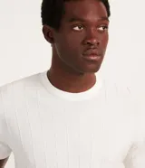 Remera slim de hombre en color blanco, con cuello redondo, mangas cortas y textura acanalada de rayas verticales.